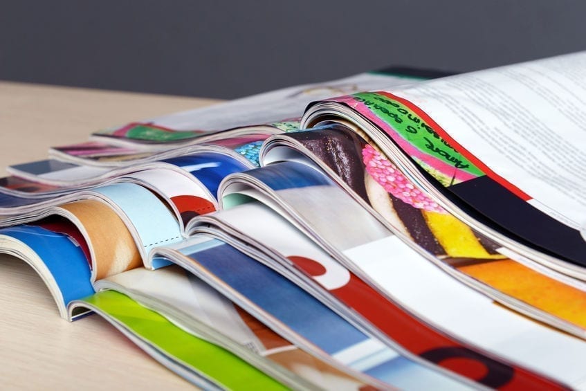 Magazines on wooden table on gray background